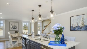 A modern kitchen with a central island, stainless steel appliances, and pendant lighting. - TJs Tide: Prime Location Condo w/ Outdoor Deck (Harwich Port)