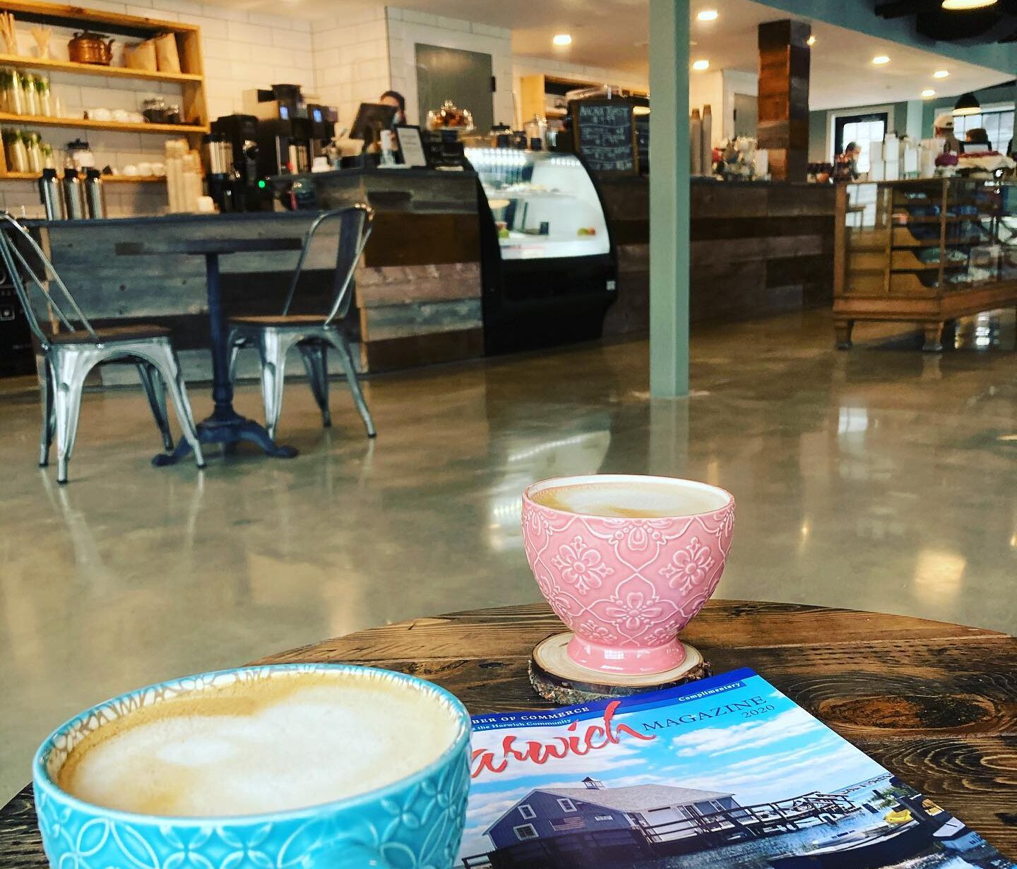 Interieur van een koffietentje met een tafel waarop een koffiekop en een tijdschrift staan.