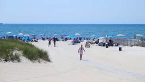 A beach with people walking, umbrellas, and beach chairs. - TJs Tide: Prime Location Condo w/ Outdoor Deck (Harwich Port)