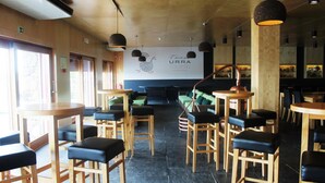 A restaurant interior with wooden tables and chairs, a large banner with the restaurant's name, and a modern ceiling design.