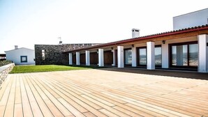 A modern building with a wooden deck, stone walls, and large windows.