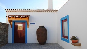 A building with a tiled roof, a large wooden door, and a large vase.