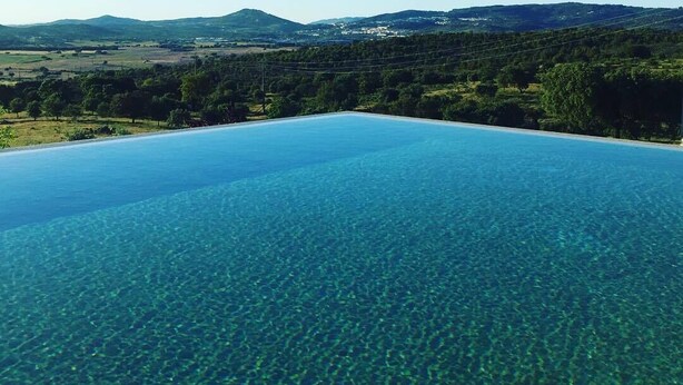 A clear view of an infinity pool with a mountain landscape in the background.