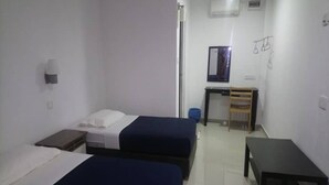 A room with two beds, a small table, and a chair. - Lembin Village Sdn Bhd (Sungai Lembing)
