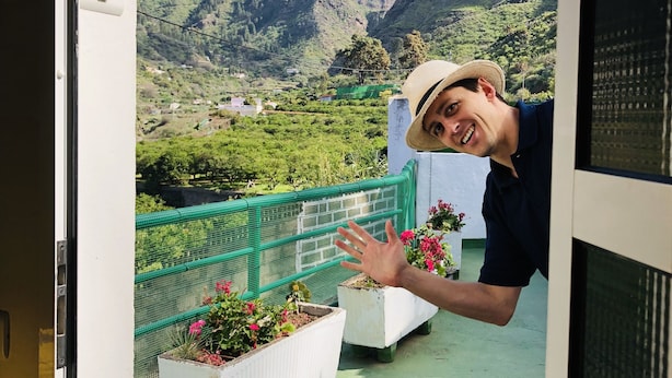 Een balkon met uitzicht op een bergachtig landschap, een groene reling en potplanten.