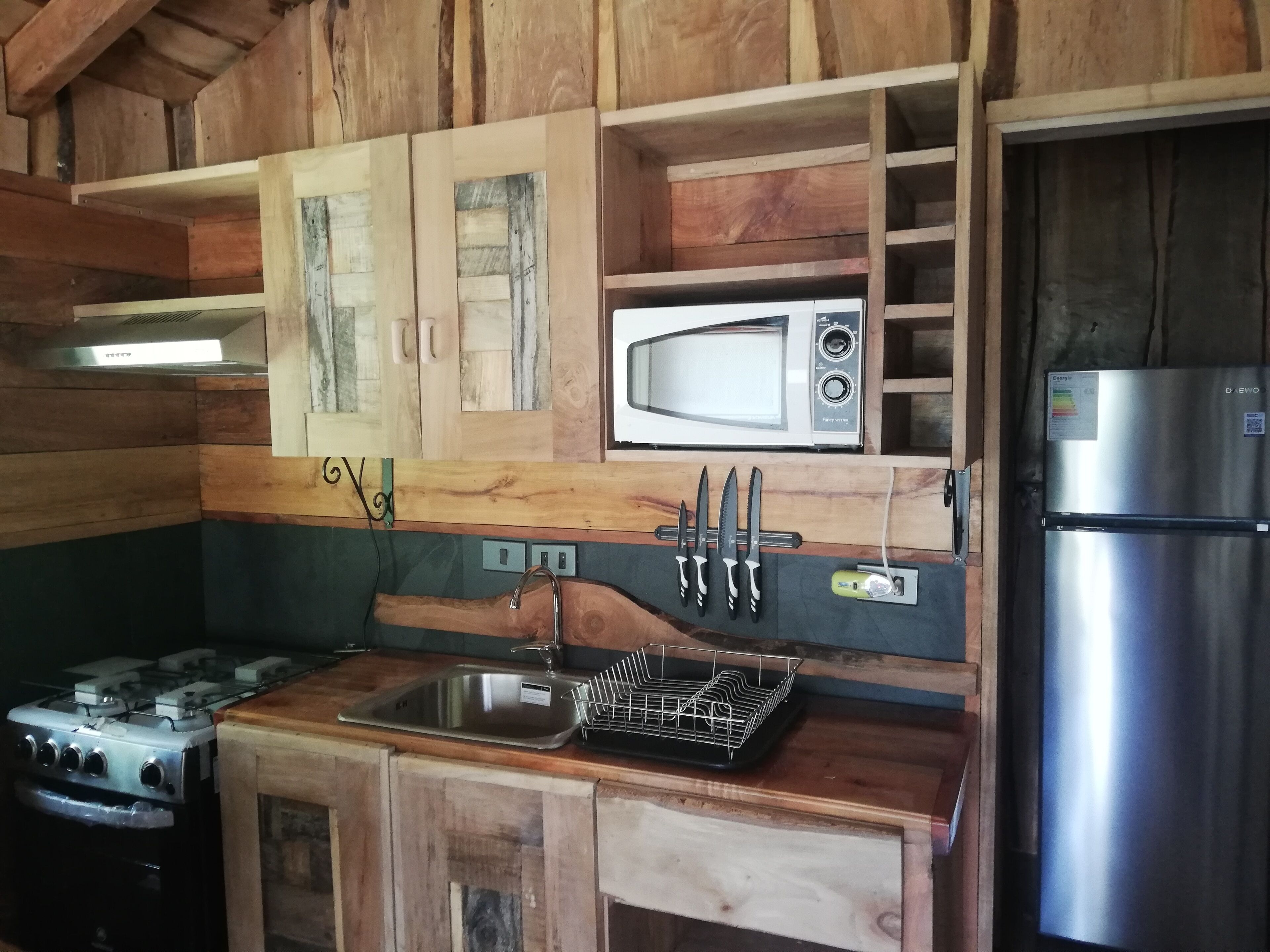 A kitchen with wooden cabinets, a microwave, a refrigerator, a sink, and a stove.