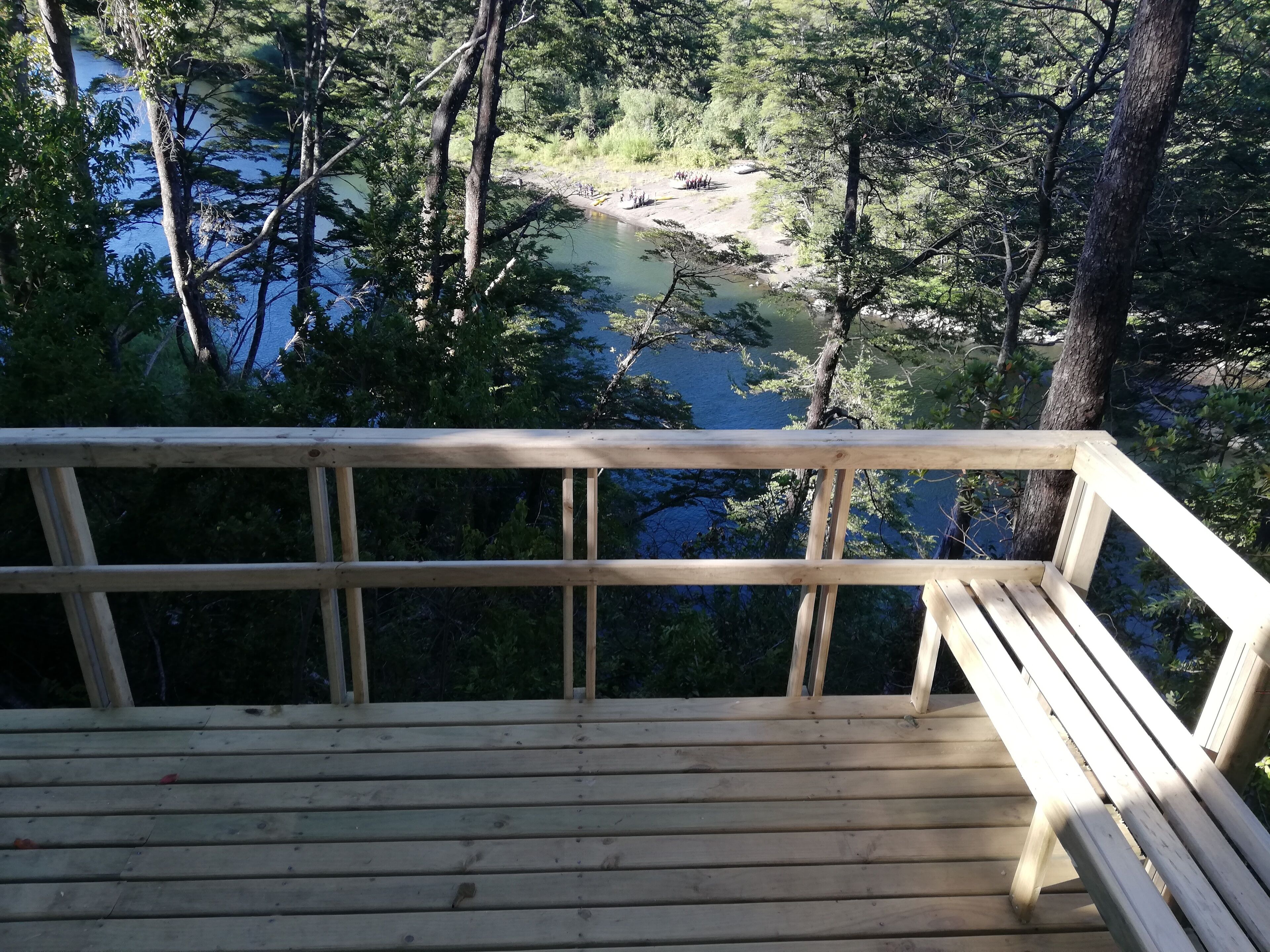 A wooden deck overlooking a river surrounded by trees.