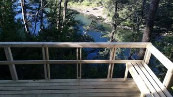 A wooden deck overlooking a river surrounded by trees.