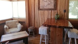 A rustic wooden interior with a wooden bench, a small stool, and a bar area. - Rustic cabins Pucón Pellín, rustic style, fully equipped. (Pucón)
