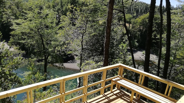 A wooden deck with a view of a river surrounded by dense forest. - Rustic cabins Pucón Pellín, rustic style, fully equipped. (Pucón)
