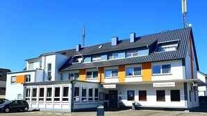 Un immeuble à plusieurs étages qui abrite un restaurant appelé « Rosengarten » au rez-de-chaussée.