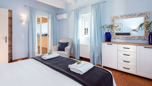 A bedroom with a bed, a chair, a dresser, and a window with curtains.
