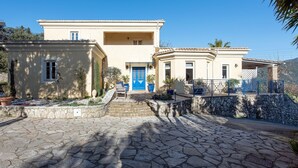 A two-story building with a blue door and a stone-paved courtyard.
