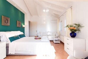 Habitación de hotel moderna con una cama, un aparador blanco, una mesita pequeña y un florero con flores.