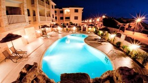 Une piscine entourée de chaises longues et de parasols, avec un bâtiment en arrière-plan.