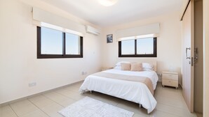 Une chambre moderne avec un grand lit, deux tables de chevet, une commode et une fenêtre avec des stores.