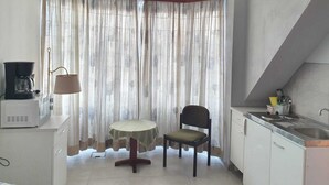 A compact kitchen with a dining table and chair, a coffee maker, and a sink. - Hotel - Pension - Weller (Muehlheim am Main)