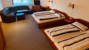 A hotel room with a sofa, a desk with a computer, two beds with striped bedding, and a window with curtains. - Hotel - Pension - Weller (Muehlheim am Main)