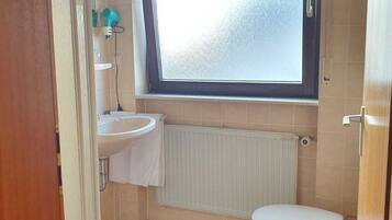 A small bathroom with a toilet, sink, and window.