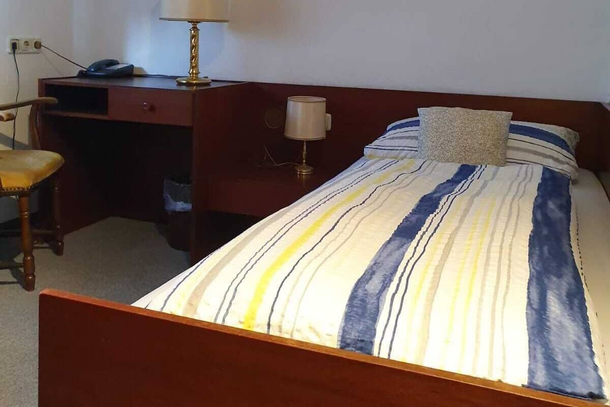 Een slaapkamer met een bed, twee bedlampen, een houten bureau en een stoel.