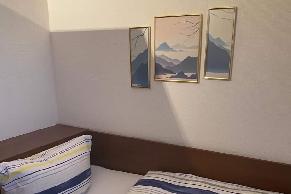 Een bed met gestreept beddengoed, een kussen en drie ingelijste foto’s aan de muur.