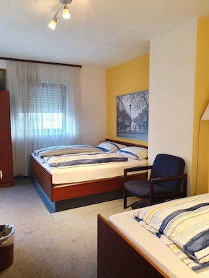 A room with a bed, a chair, a desk, a window with curtains, and a painting on the wall. - Hotel - Pension - Weller (Muehlheim am Main)