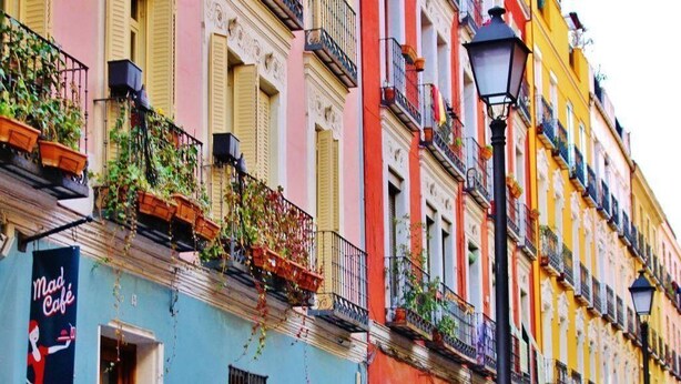 Una hilera de edificios coloridos con balcones, un farol y el letrero de un café.