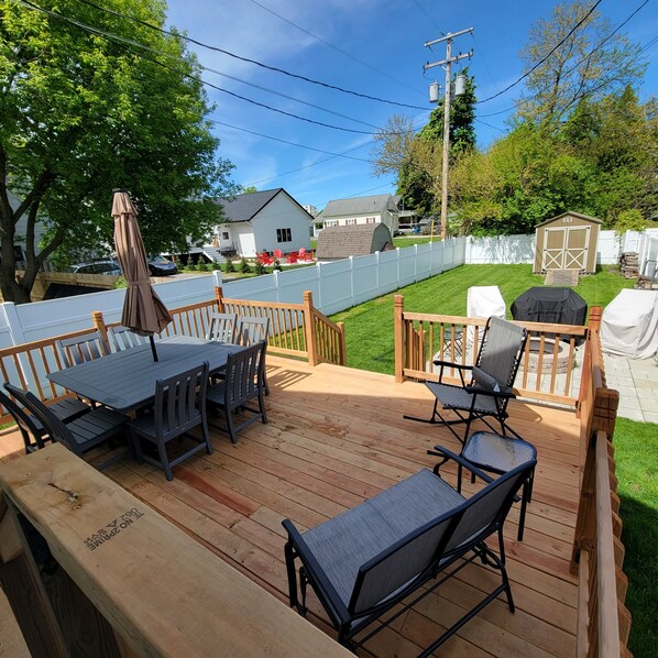 A wooden deck with a table and chairs, a grill, and a small shed. - Beautifully redone, fenced yard, fire pit, close to the lake
(Grand Haven)