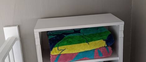 Un estante blanco con mantas coloridas y un cartel que dice 'The beach is where my heart is'.