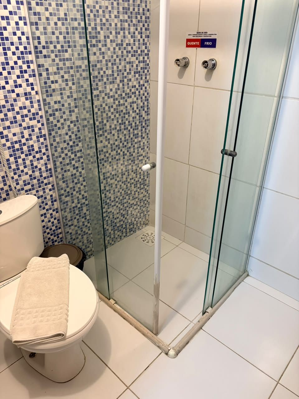 Une salle de bain avec une douche à parois de verre, des toilettes et un mur carrelé.