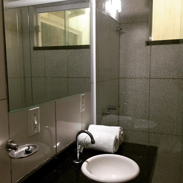 A bathroom with a glass-enclosed shower, a white sink, and a mirror.