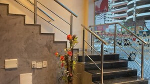 Un escalier moderne agrémenté d’une plante en pot, d’un tableau coloré et offrant une vue sur un bâtiment à l’extérieur.