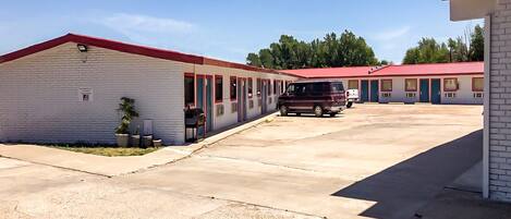 A row of motel buildings with a parking lot in the foreground.