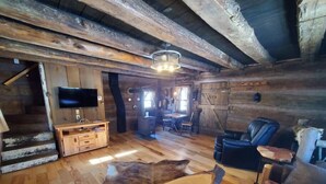 Ein rustikales Ferienhaus-Interieur mit einer Holztreppe, einem Flachbildfernseher, einem Essbereich und einem Ledersofa.
