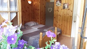 A wooden cabin with two beds, a window with curtains, a wall-mounted light, and a door with a heart-shaped decoration. - Termignon Val cenis Vanoise (Termignon Val cenis)