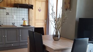 A modern kitchen with wooden cabinets, a tiled backsplash, and a dining area with a table and chairs. - Termignon Val cenis Vanoise (Termignon Val cenis)