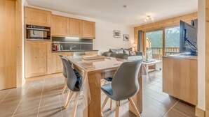 A modern kitchen with wooden cabinets, a dining table with chairs, and a balcony with a view of the mountains. - 50m from ski slopes, 9th floor, balcony, parking, tv, ski locker, 52m², Champagny-en-Vanoise (Champagny-en-Vanoise)