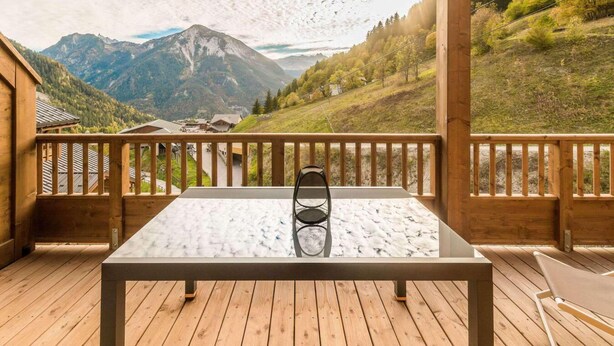 A wooden deck with a table and chairs, overlooking a mountainous landscape. - 50m from ski slopes, 9th floor, balcony, parking, tv, ski locker, 52m², Champagny-en-Vanoise (Champagny-en-Vanoise)