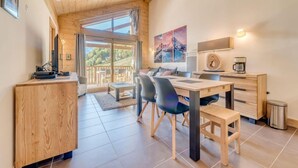 Une cuisine moderne avec un coin repas, des meubles en bois et une grande fenêtre donnant sur l’extérieur.