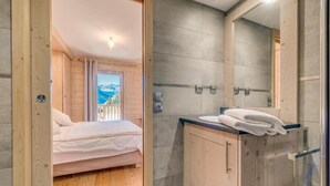 Quarto com piso de madeira, uma cama e banheiro com pia e espelho.