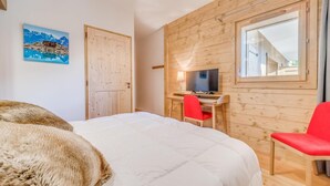Ein Schlafzimmer mit einem Bett, einem Schreibtisch mit Stuhl, einem Fernseher und einem Fenster.