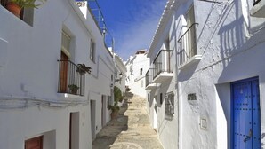 Eine enge Straße mit weißen Häusern, blauen Türen und einer Treppe, die zu einer höheren Ebene führt.