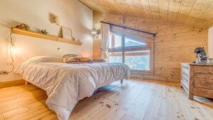 Une chambre confortable avec un lit, un plancher en bois, une fenêtre donnant sur un beau paysage et une commode.