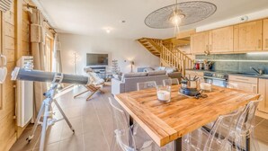 Une cuisine moderne avec des meubles en bois, une table à manger et un escalier menant à l’étage supérieur.