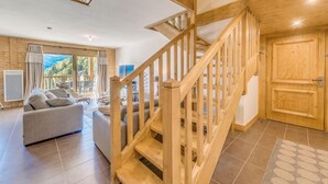 Un vaste espace de vie agrémenté d’un escalier en bois, d’un canapé et offrant une vue sur l’extérieur.