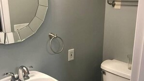 A bathroom with a white sink, a round mirror, a toilet, and a towel rack. - Delightful Guest Room Close to Hendersonville’s Downtown (Hendersonville)