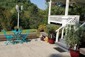Une terrasse avec des meubles d’extérieur, un escalier blanc et des plantes en pot.