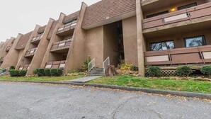 A multi-story building with balconies, a central entrance, and a parking area. - Spacious 2BR Apartment in Prime Location (Chattanooga)