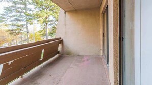 A balcony with a concrete floor, a wooden railing, and a glass door. - Spacious 2BR Apartment in Prime Location (Chattanooga)
