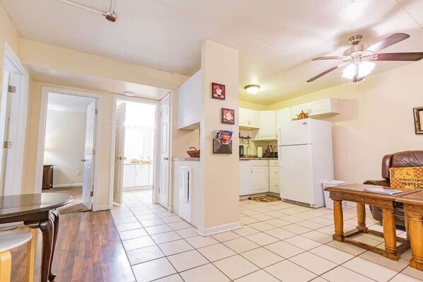 A spacious kitchen with white cabinets, a refrigerator, and a ceiling fan.
